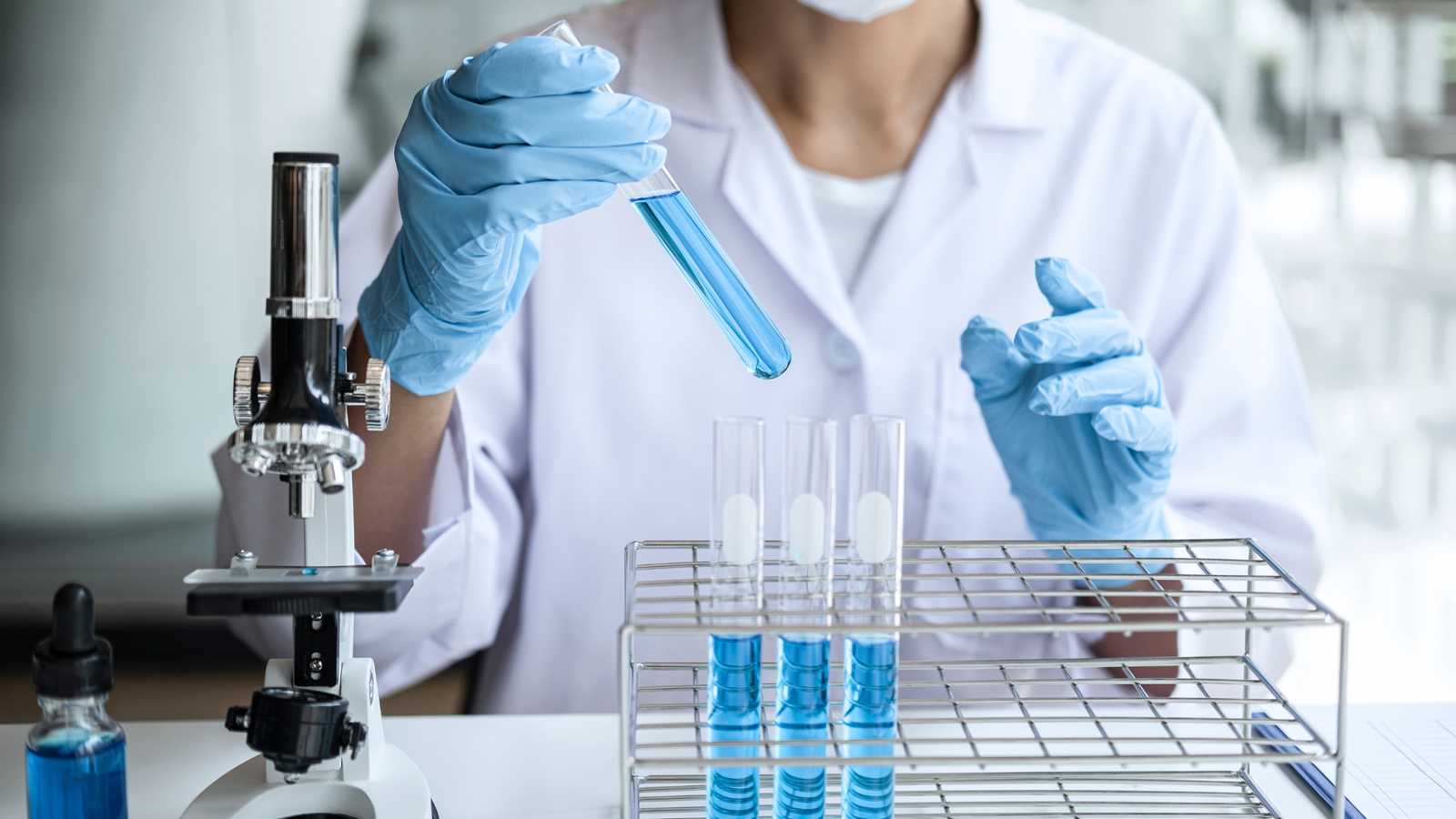 Científica manipulando tubos de ensayo en un laboratorio.