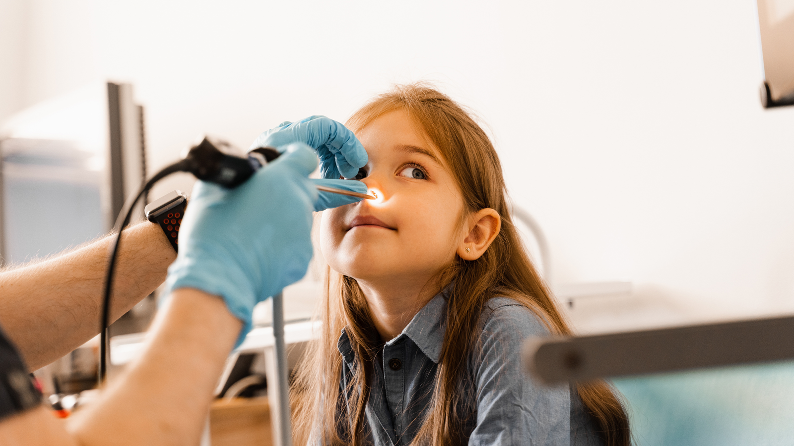 Niña siendo examinado en la nariz por un médico con un endoscopio.